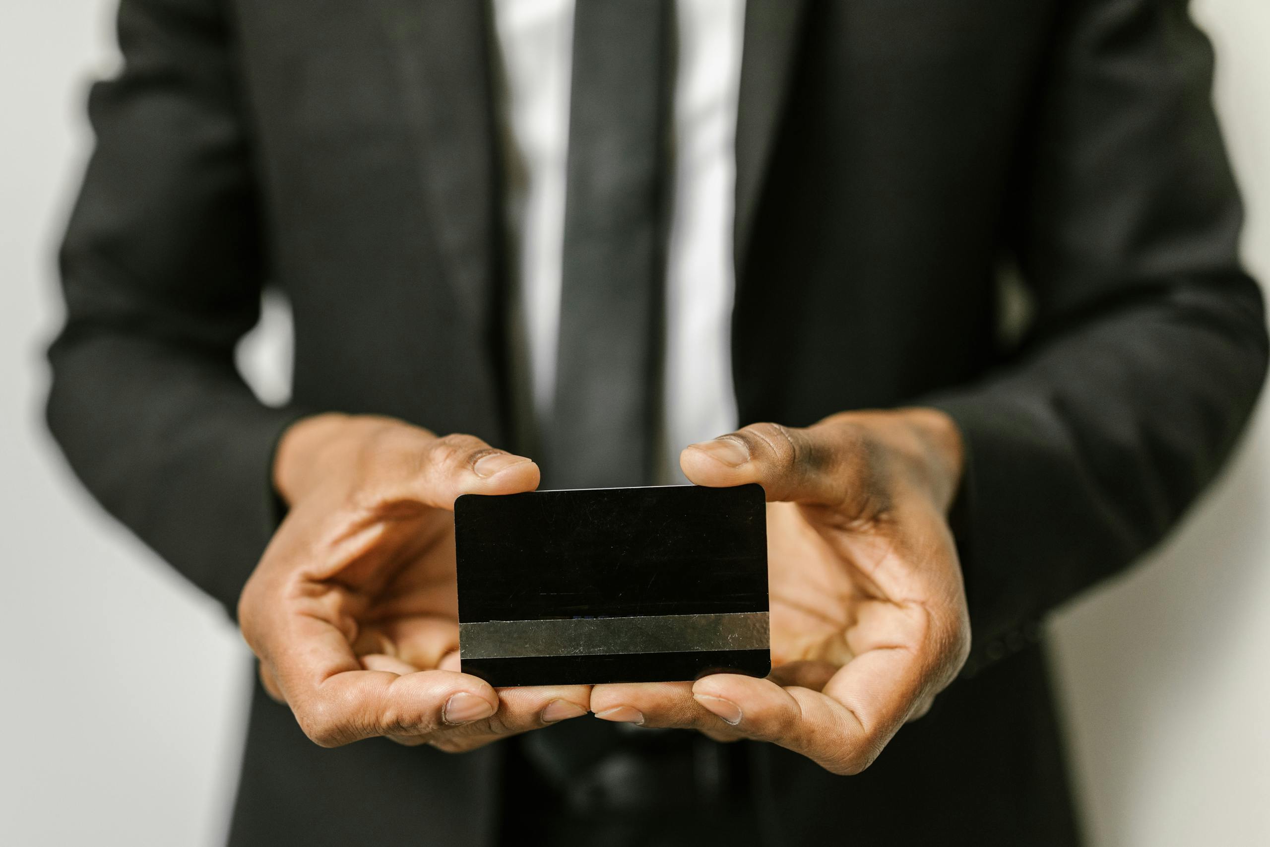 Close-up of a businessman holding a blank credit card with both hands, emphasizing finance.